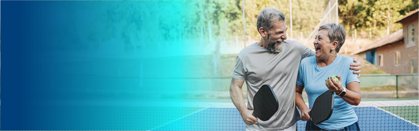 Two people smiling while holding pickleball paddles.