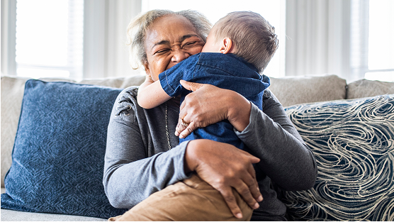 Older adult hugging a child on a sofa.