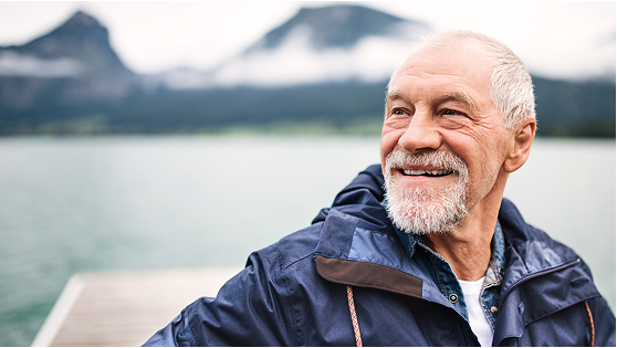 Person walking outdoors near a lake, smiling.