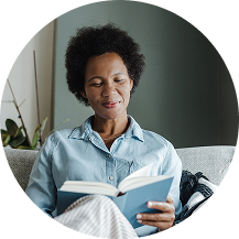 Person sitting on couch reading a book with a calm expression.